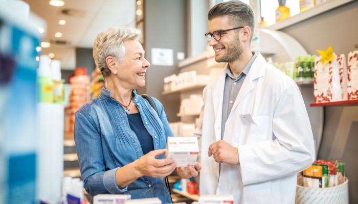 Farmacéutico hablando y asesorando a un paciente en la farmacia