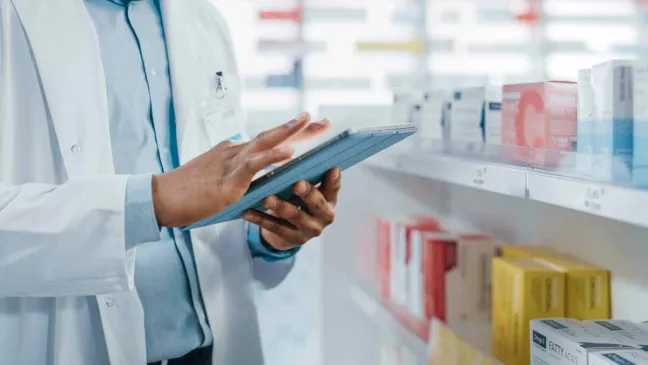 Farmacéutico revisa la tablet ante medicamentos farmaceutico-con-tablet