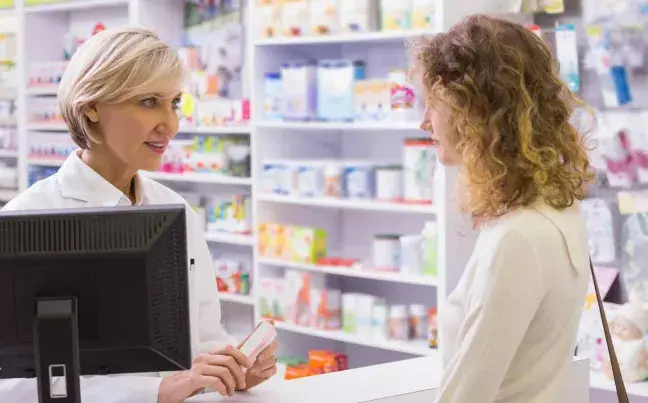 Farmacéutica explica a paciente en el mostrador farmaceutica-y-mostrador