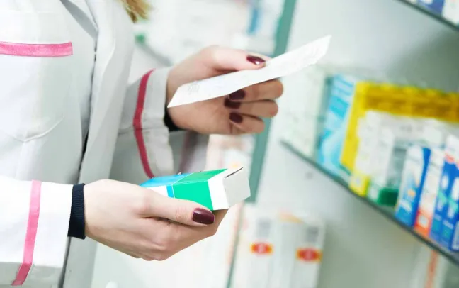 Farmacéutica coge un medicamento con la receta médica farmaceutica-con-medicamento