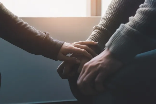 Persona toca la mano de otra persona manos-en-rodillas