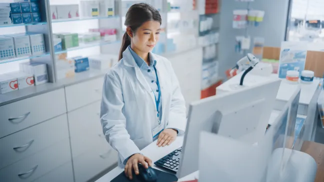 Farmacéutica utiliza el ordenador en el mostrador farmaceutica-utilizar-ordenador
